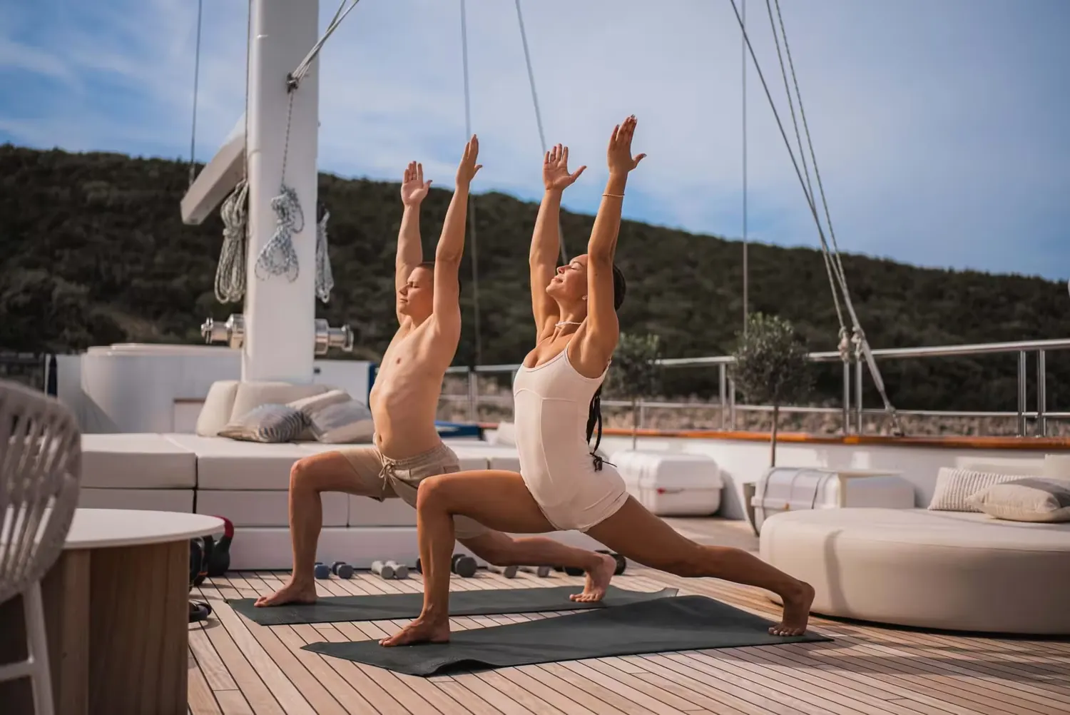 Twee gasten doen yoga op het teakdek